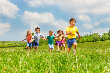 Obraz premium Running kids in green field during summer