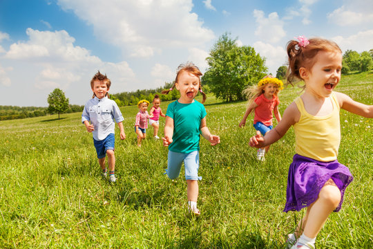 Excited running kids in green field play together