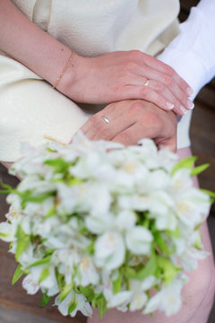 Hands of bride and groom holding wedding bouquet