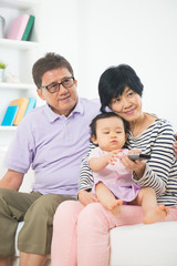 Obraz premium asian grand parents watching television with grand daughter life