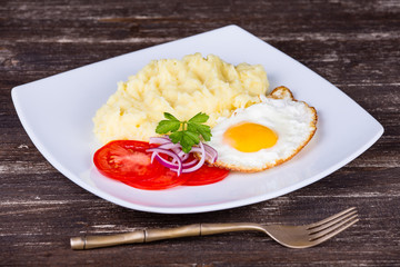 Mashed potatoes with fried eggs and tomato