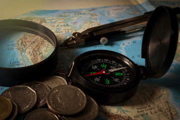 Compass with magnifier and coins on map