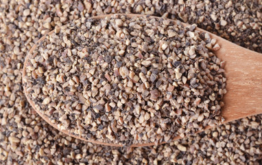 heap of powdered black pepper on a wooden spoon