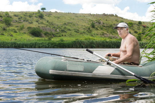 Senior man fishing from a rubber dinghy