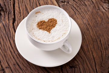 Cup of cappuccino with ground cinnamon in the form of heart.