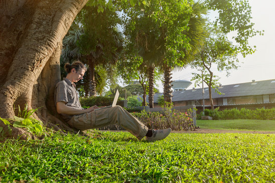 Yang business man is relaxing outdoors with laptop