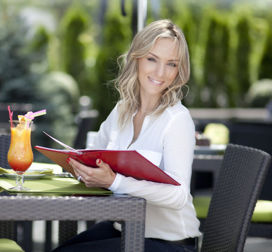 Portrait of young beautiful woman sitting in a cafe outdoor drin