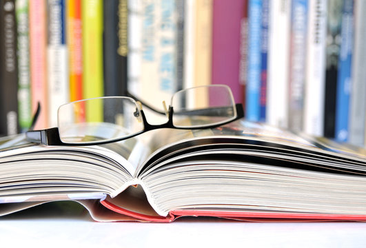 Offenes Buch mit B&uuml;cherreihe im Hintergrund