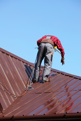 Roofer builder worker with pulverizer spraying paint on roof