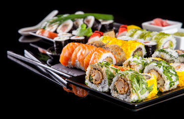 Delicious sushi pieces on black background