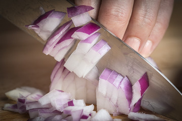 Cortando cebolla con un cuchillo en la cocina sobre la tabla