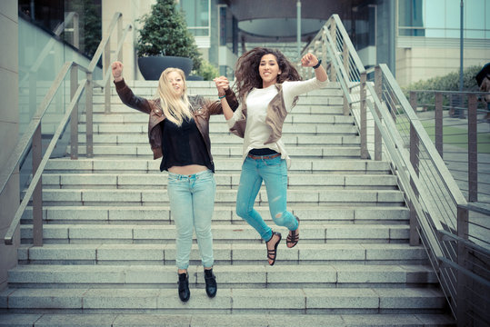 Happy young women jumping mid air on steps outdoors
