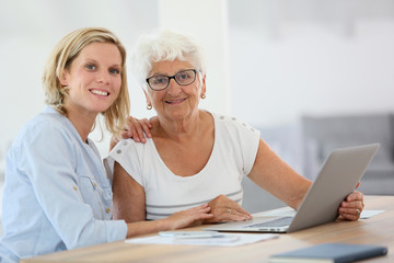 Fototapeta na wymiar Homecarer with elderly woman using laptop computer