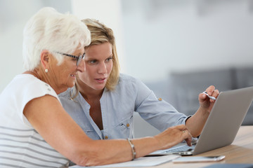 Homecarer with elderly woman using laptop computer
