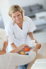 Homecarer giving tea to elderly woman