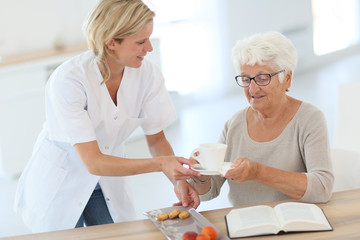 Fototapeta na wymiar Homecarer giving tea to elderly woman