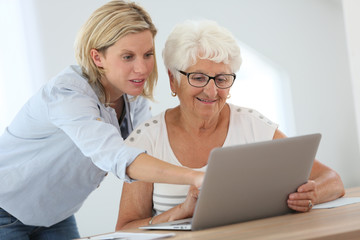 Homecarer with elderly woman using laptop computer