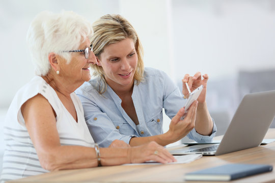 Homehelp with elderly woman using smartphone