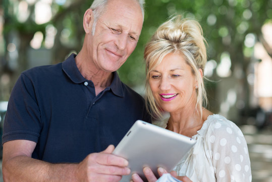 aktives seniorenpaar schaut auf tablet-pc