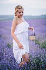 Fototapeta na wymiar Beautiful young girl posing in a lavender field