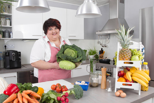 Chubby smiling woman in the kitchen making diet.