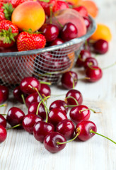 fresh berries and fruits in metallic basket on wooden surface