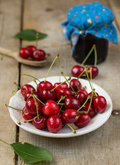 Cherries in a white plate on wooden background