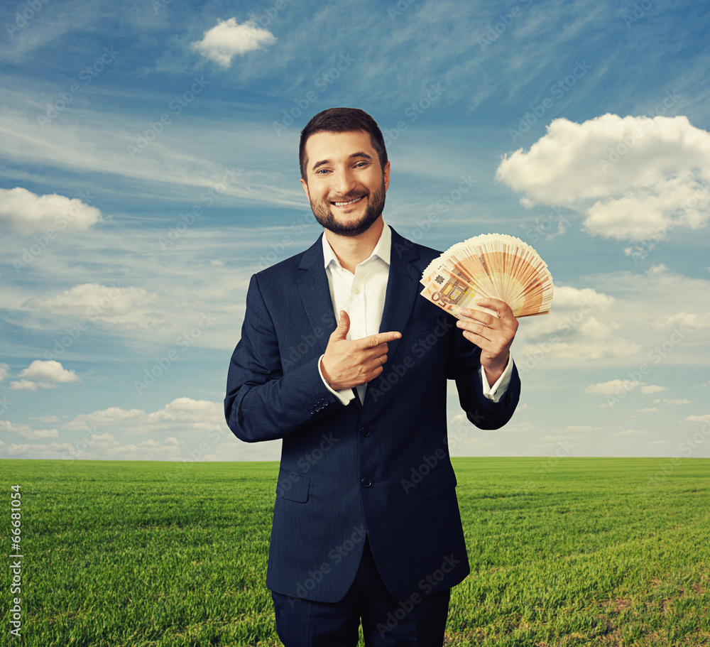 Wall mural man pointing at paper money at outdoor