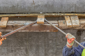 builder workers removing formwork elements with crowbar