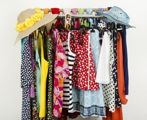 Cute colorful summer clothes and wicker hats hanging on a rack.