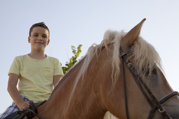 Niño con camiseta amarilla montado a caballo