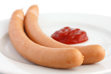 Two frankfurter sausages on a plate with ketchup
