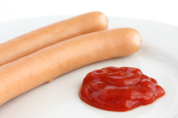 Two frankfurter sausages on a plate with ketchup