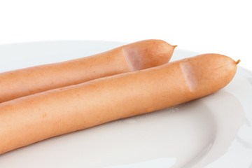Two cooked frankfurter sausages on a plate with white background