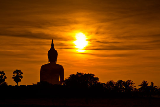 Big buddha statue at Wat Muang with sunset sky in Thailand