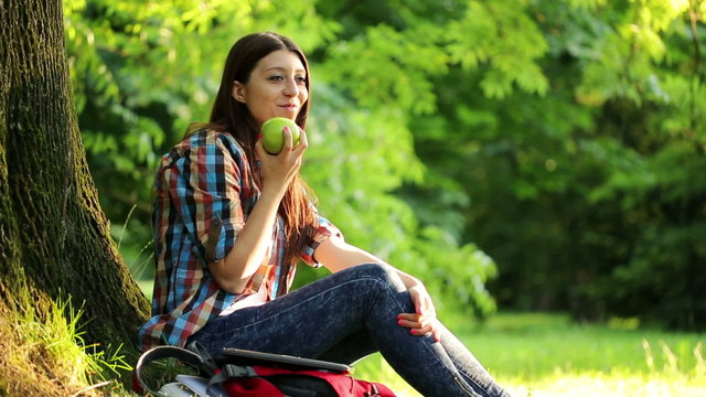 Young Beautiful Teenager Eating Green Apple In The Park