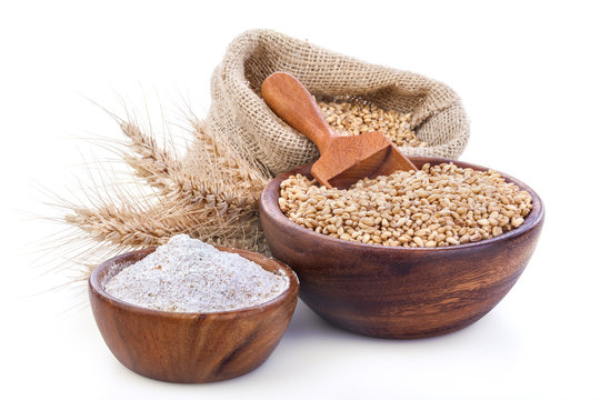 Ripe wheat and flour in a wooden bowls