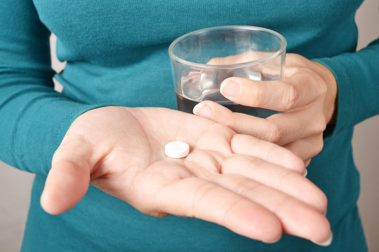 person taking a pill with a glass of water