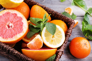 Fresh citrus fruits with green leaves in wicker basket