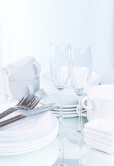 Set of white dishes on table on light background