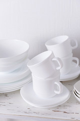 Fototapeta na wymiar Set of white dishes on table on light background