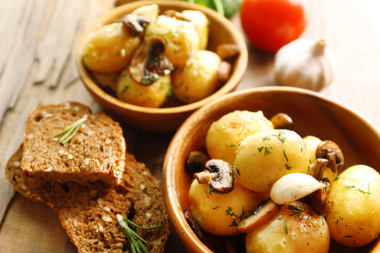 Young boiled potatoes in bowl on wooden table, close up