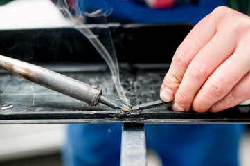 Professional mechanic using a plastic and synthetic welder