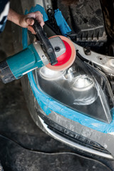 mechanic cleaning headlights with polishing power buffer machine