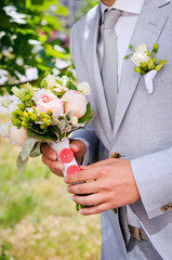 A man in a gray suit with a wedding bouquet