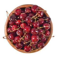 Red cherries in a wooden bowl on a white