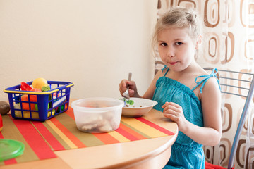 Young child plays with toys at table and eating