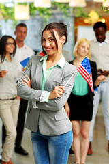 Smiling businesswoman holding flag of USA in front of colleagues