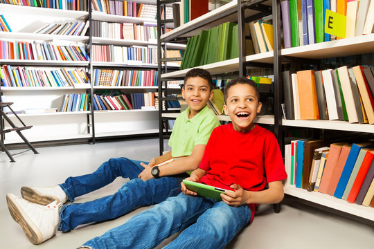 Two laughing boys sitting on the floor in library