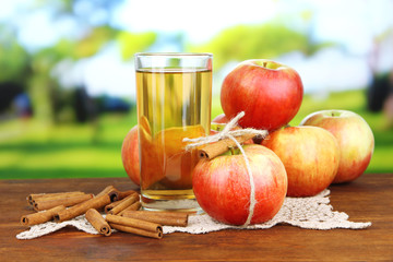 Ripe apples with with cinnamon sticks and glass of  apple drink